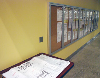 Plans under review sit on a table in the Ann Arbor city hall lobby, next to the glass cases that hold public notices.