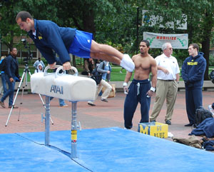 Members of the UM men's gymnastics team perform on the Diag. Head Coach Kurt Golder was there too, wearing a white polo shirt.