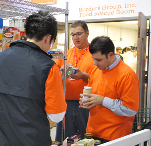 Orange team members check expiration dates in the Food Gatherers pantry.