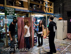 Crew members do last-minute work in the backstage paint shop.