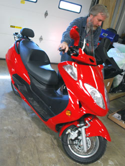 Guy rolling a red electric motorcycle into place