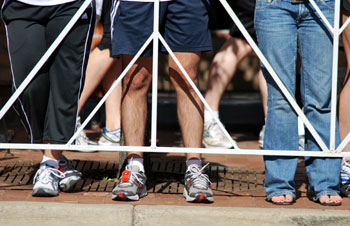 legs standing behind a barrier and a running race