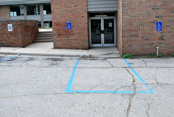 Ann Arbor Community Center at entrance showing need for upgrade in wheelchair ramp, and signage wih van accessible language