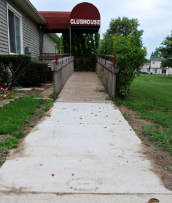 concrete landing for wheelchair ramp equipped with handrails and siderails.