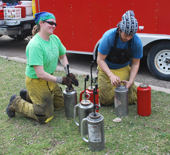 Two burn crew members prepare drip torches