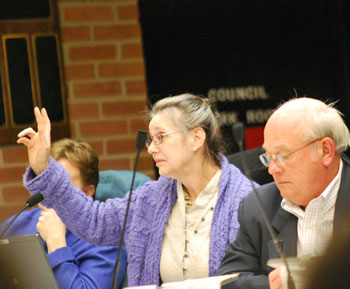 Sabra Briere with her hand raised to speak