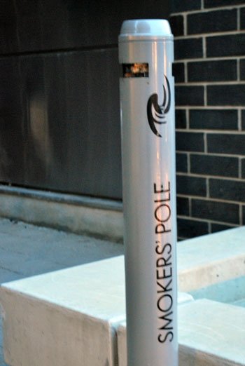 A pole for disposing of cigarette butts placed outside the Ann Street entrance to Ann Arbor's city hall building.